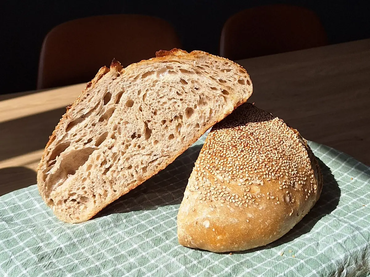 Twee versgebakken zuurdesembroden op een houten plank in het zonlicht